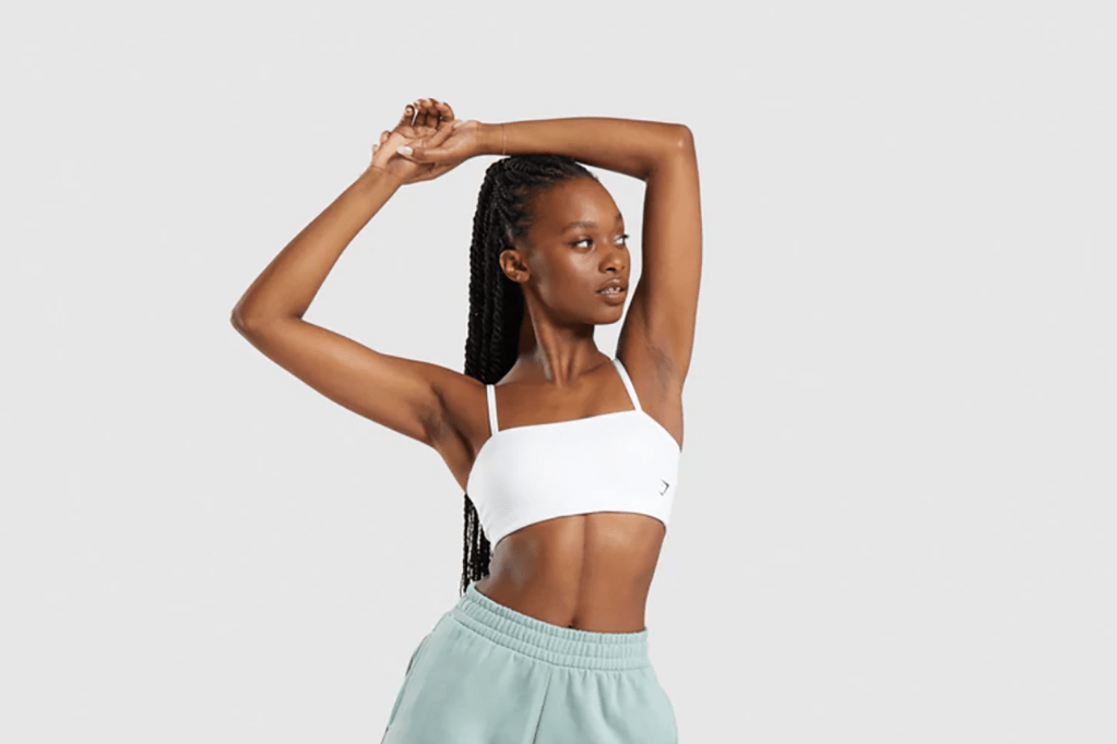 A woman in a white sports bra stretching 