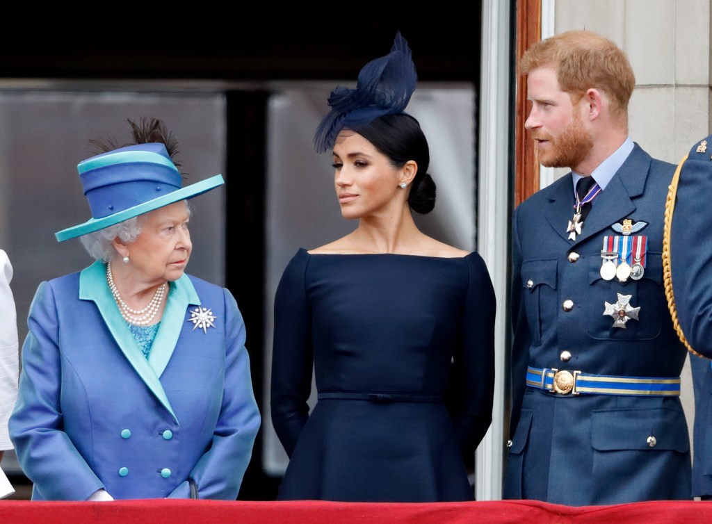 Queen Elizabeth II, Meghan, Duchess of Sussex and Prince Harry, Duke of Sussex watch a flypast to mark the centenary of the Royal Air Force from the balcony of Buckingham Palace.