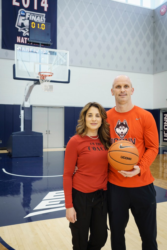 Andrea and Danny Hurley, basketball coach at University of Connecticut, standing in a gym holding a basketball