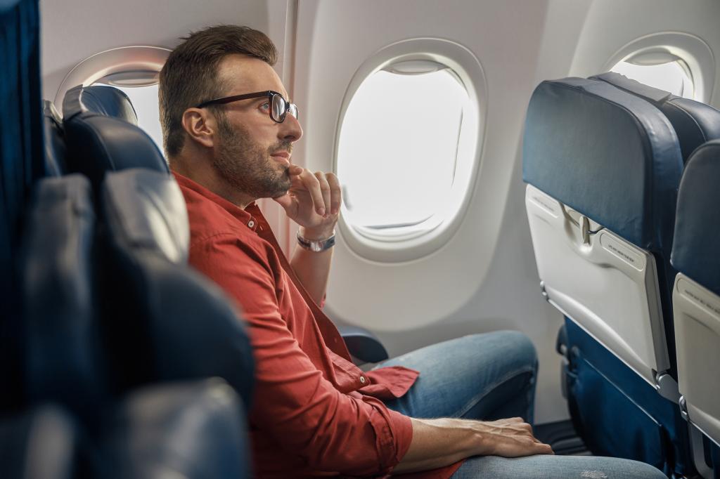 Man on an airplane sans distractions, thinking. 