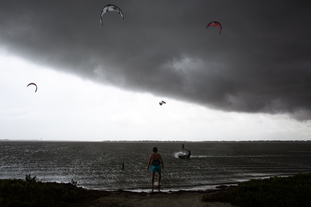 Kiteboarder Kuba Krzycki stands on the shore and watches kitesurfers in Oso Bay as the outer edge of Hurricane Beryl moves into Corpus Christi on Sunday afternoon. 