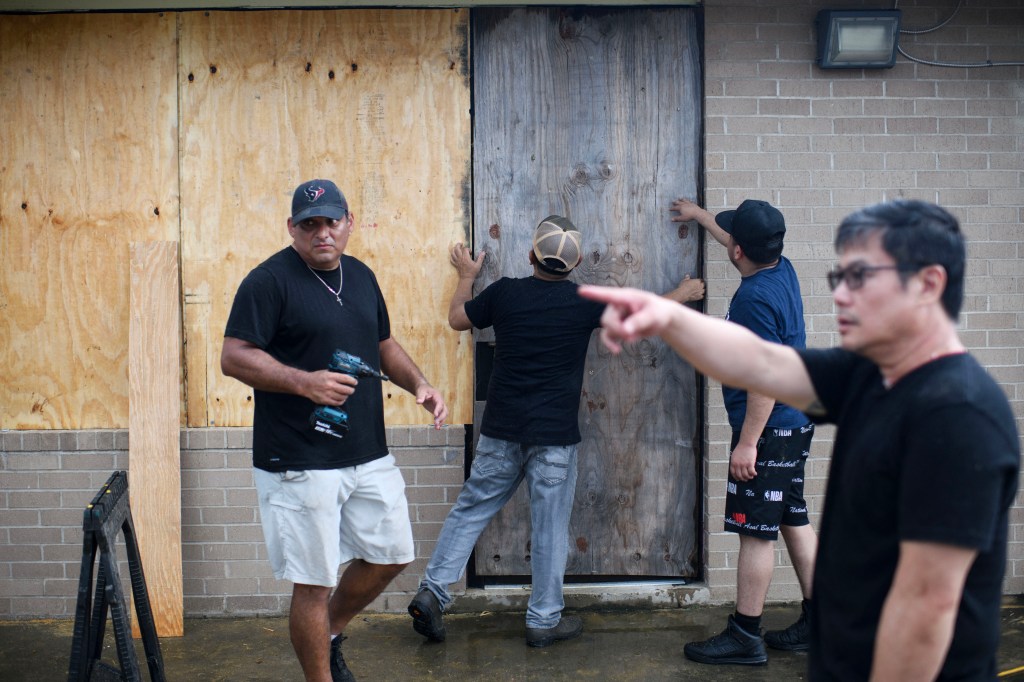 A group of men board up a restaurant in Port Lavaca, Texas, on July 7, 2024, as they prepare for the arrival of Hurricane Beryl