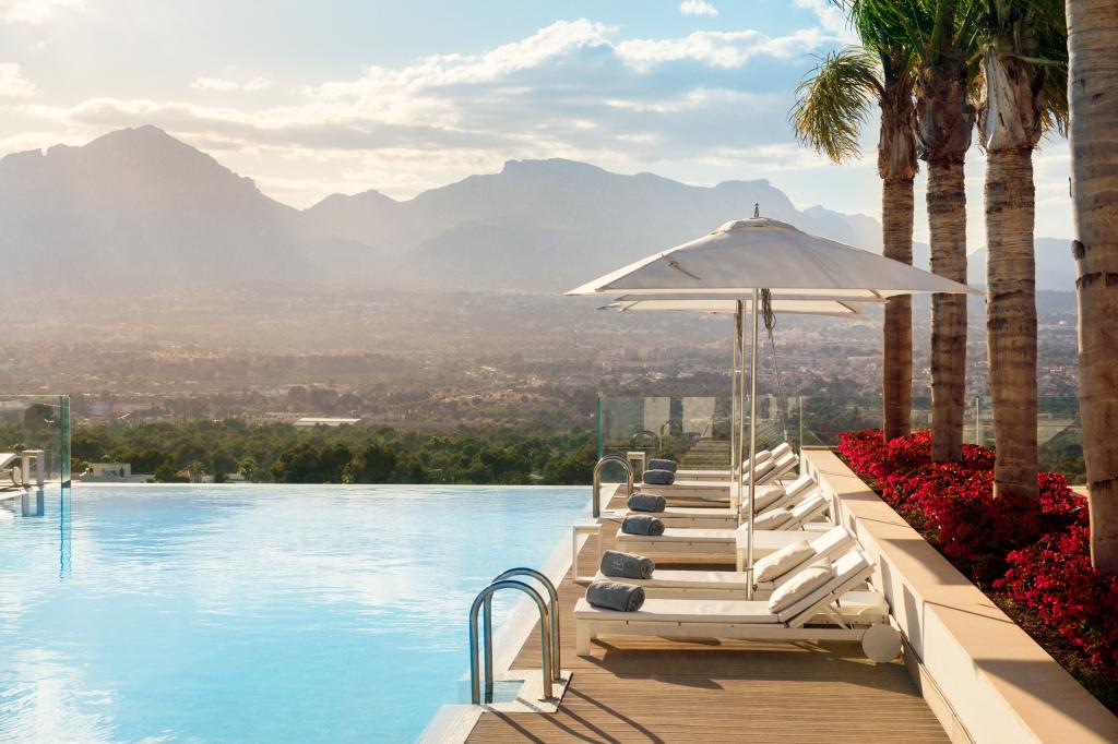 A pool with chairs and umbrellas overlooking mountains at the SHA Wellness Clinic Spa