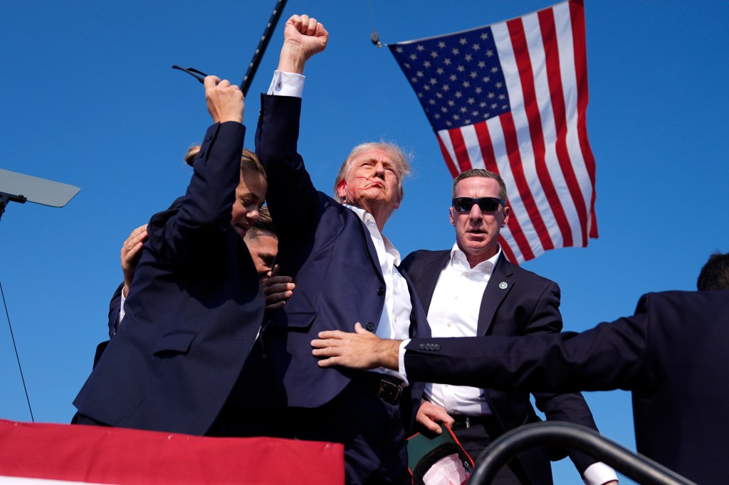 Republican presidential candidate former President Donald Trump gestures as he is surrounded by U.S. Secret Service agents as he leaves the stage at a campaign rally, July 13, 2024, in Butler, Pa.