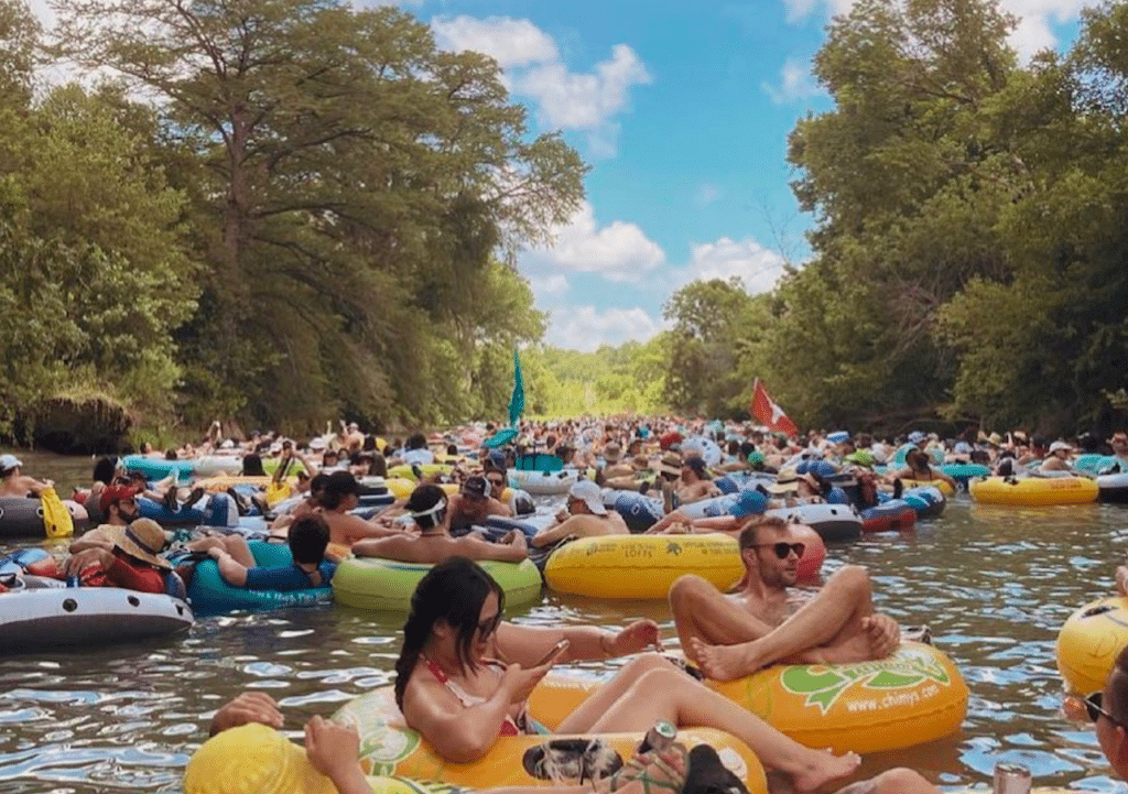 Image shows a group of people tubing a river in Texas's city of San Marcos.