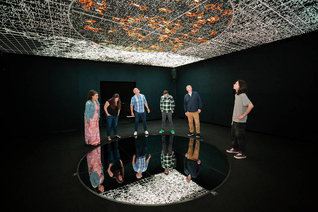 Image shows a group of people admiring the Ryoji Ikeda audiovidual art installation at THE INFINITE in Houston.