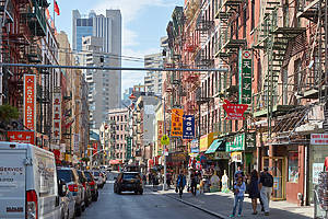 NEW YORK - SEPTEMBER 7: Chinatown street with cars and people and buildings in a sunny day on September 7, 2016 in New York. The district hosts the largest Chinese enclave in the Western Hemisphere.