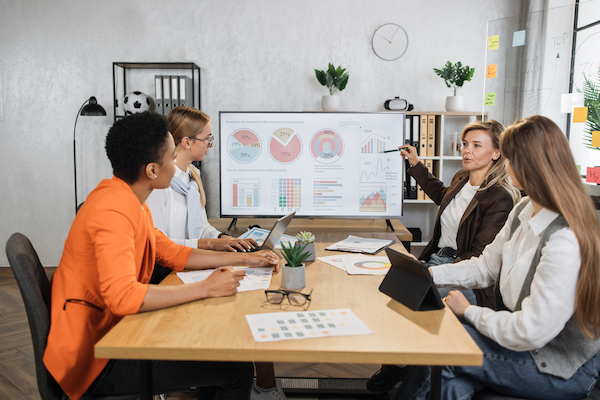 four female partners sitting at desk and discussing