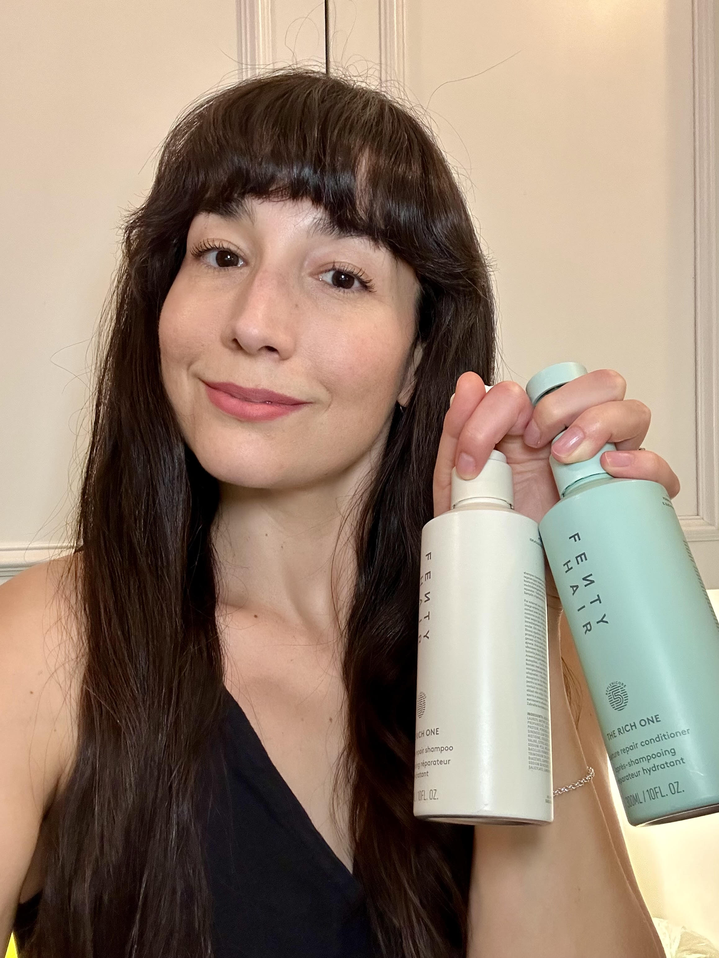 A brunette woman holding up a shampoo and conditioner