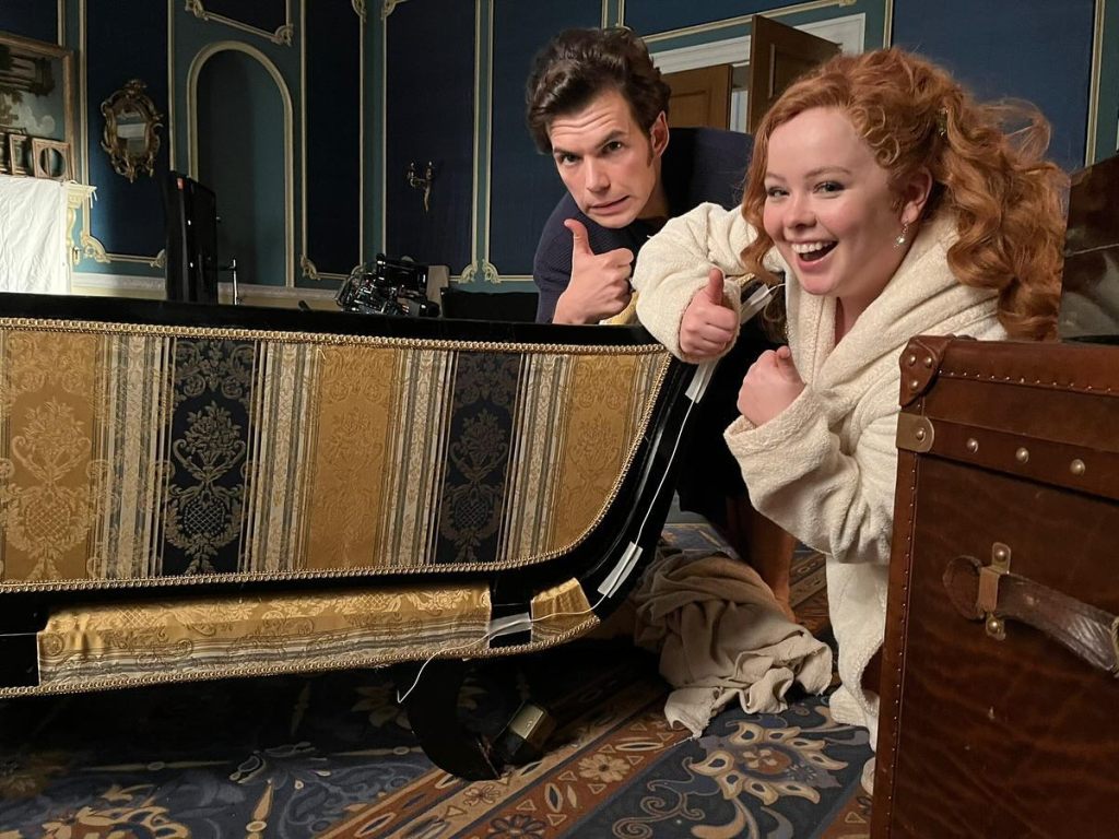 Nicola Coughlan and Luke Newton next to a piece of furniture they broke during a scene.