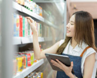 Woman at drink fridge in store looking at products