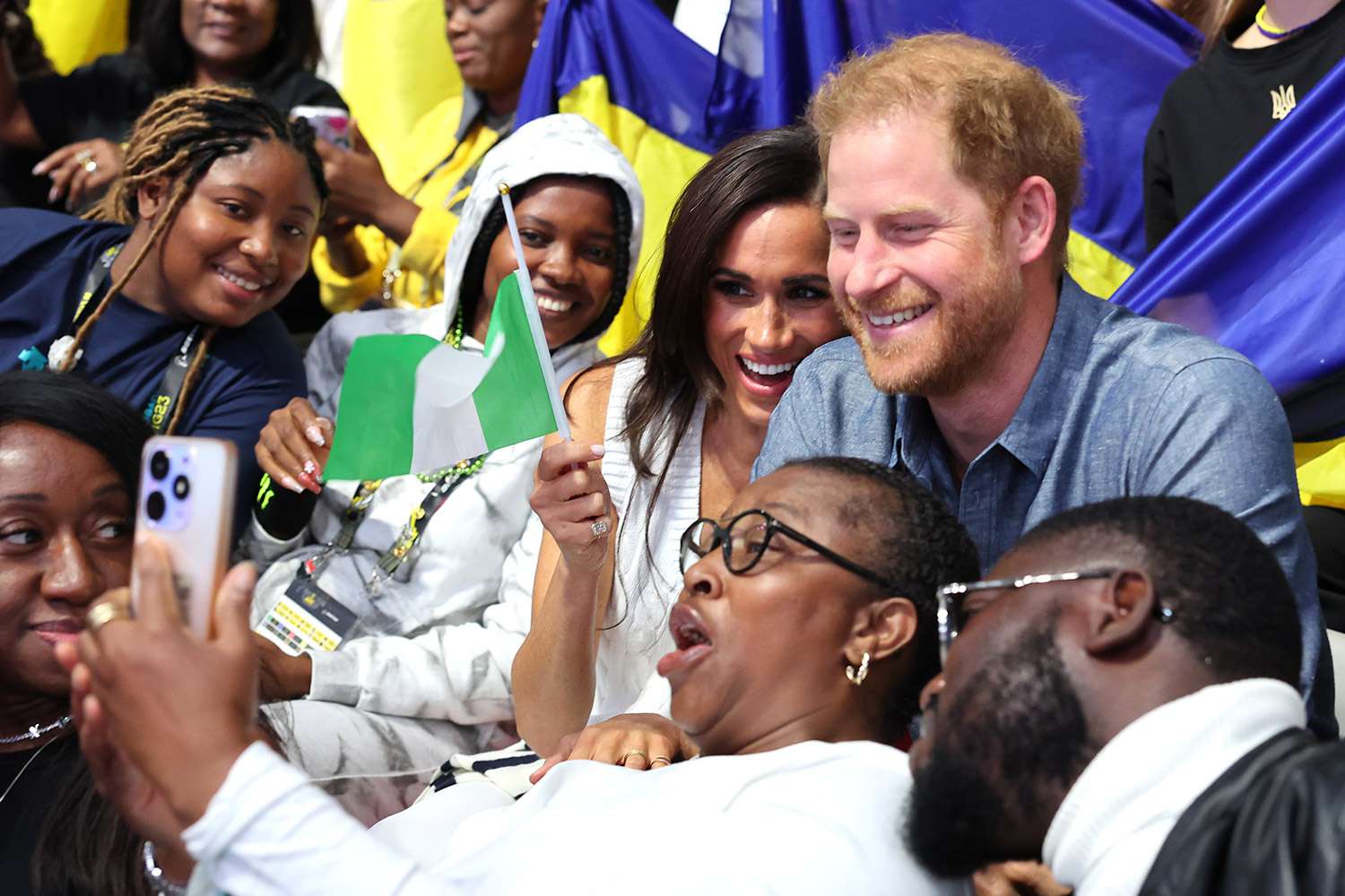 Meghan, Duchess of Sussex Prince, and Prince Harry, Duke of Sussex, take selfies with fans as they attend the Ukraine Nigeria Mixed Team Preliminary Round - Pool A Sitting Volleyball match during day five of the Invictus Games Duesseldorf 2023 on September 14, 2023 in Duesseldorf, Germany