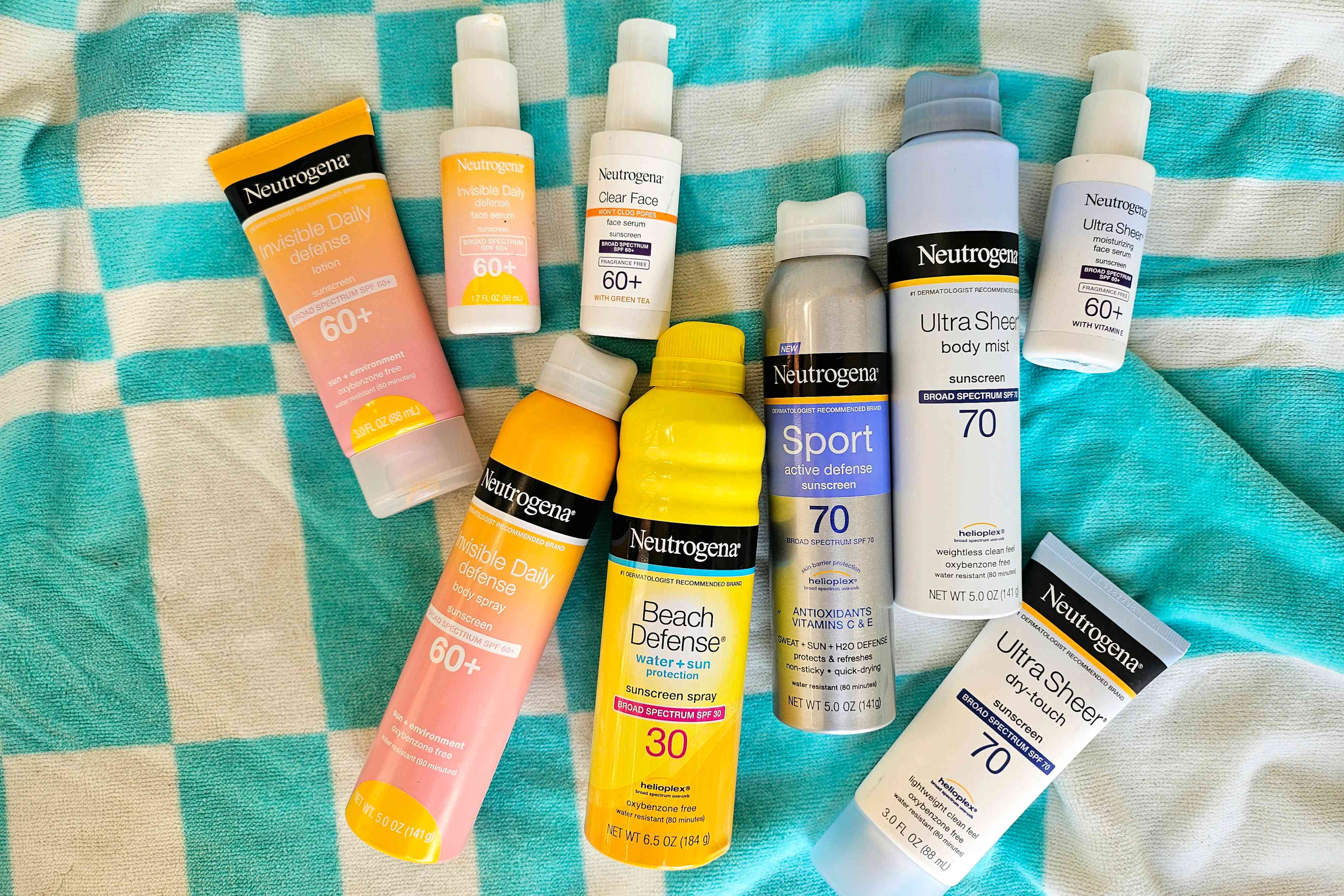 An assortment of Neutrogena sunscreen products on a teal and white beach blanket 