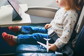 Stock image of a toddler using a digital tablet during a flight