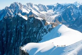 Mont Blanc mountaneers walking on snowy ridge.