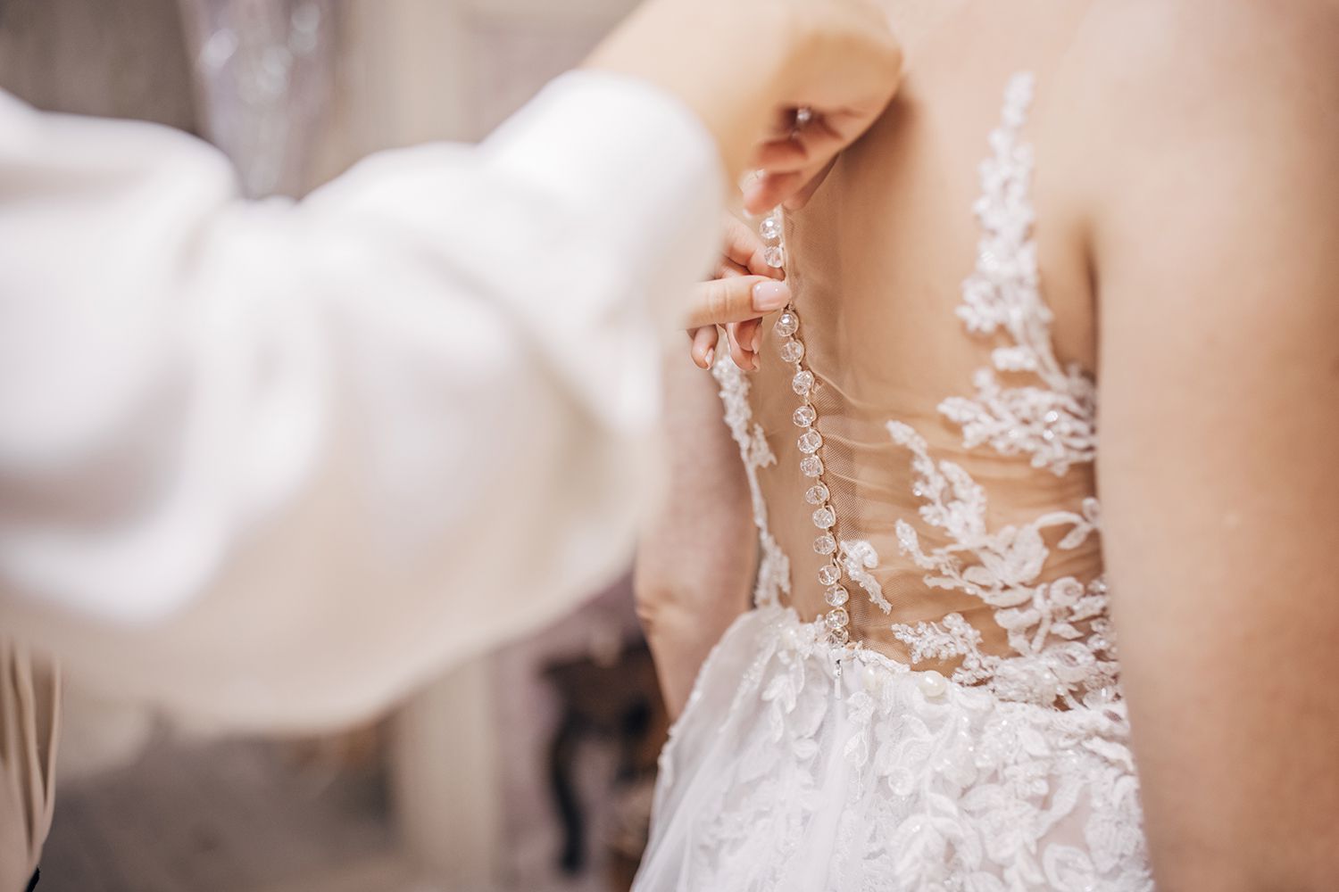 Bride wearing her wedding dress, while her female dress designer making final adjustments on dress.