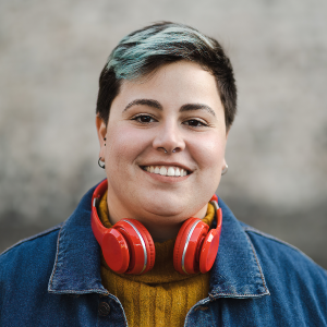 Non-binary person with red headphones smiling