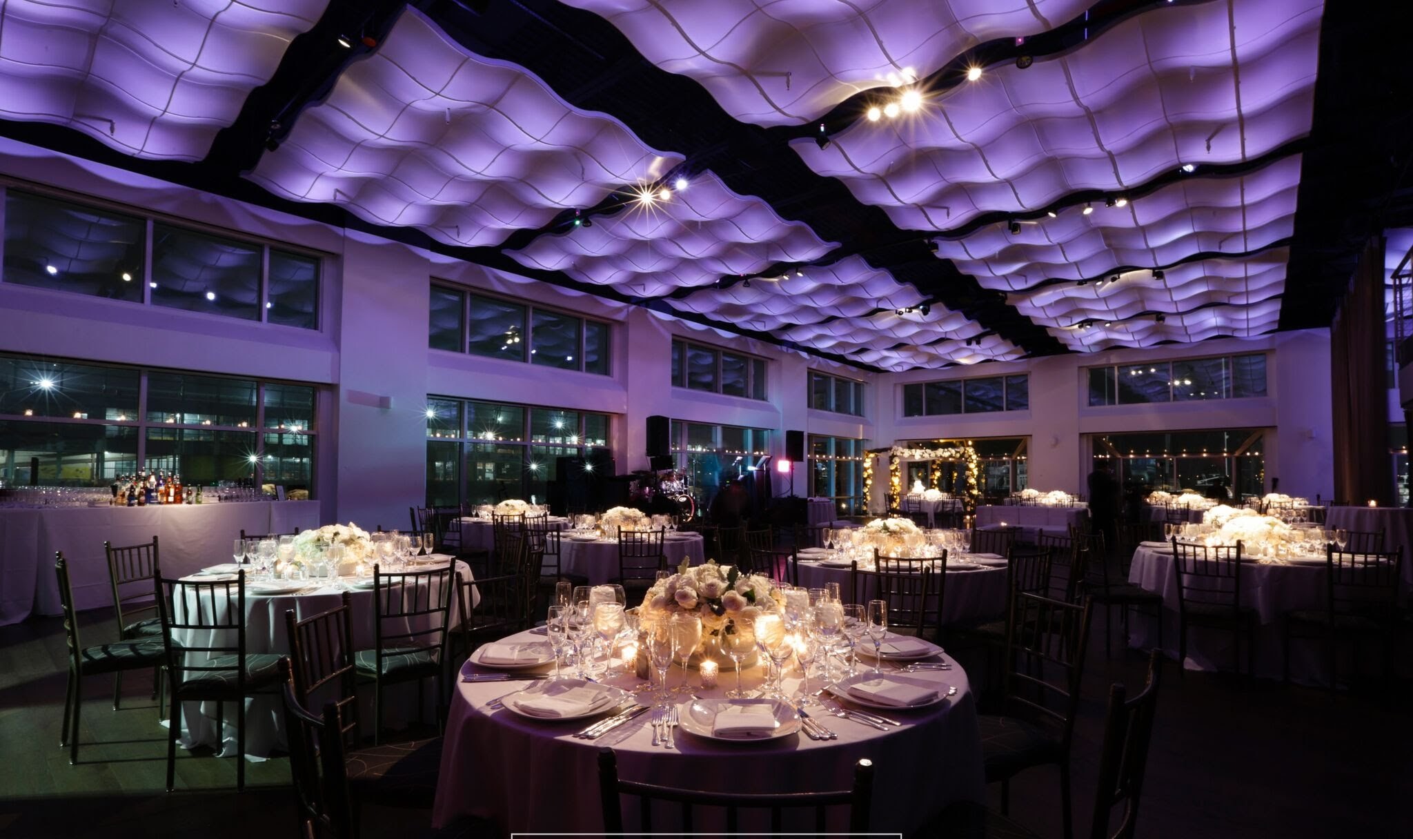 Round Tables set for dinner with purple lighting and candles on the tables