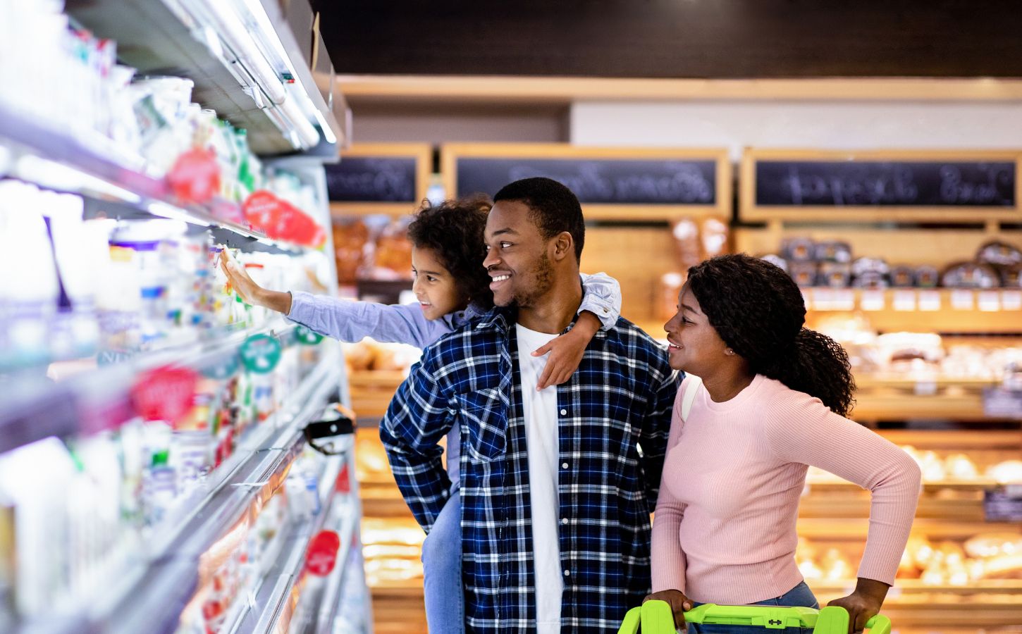 Photo shows a young family shopping in the refrigerated section of a supermarket