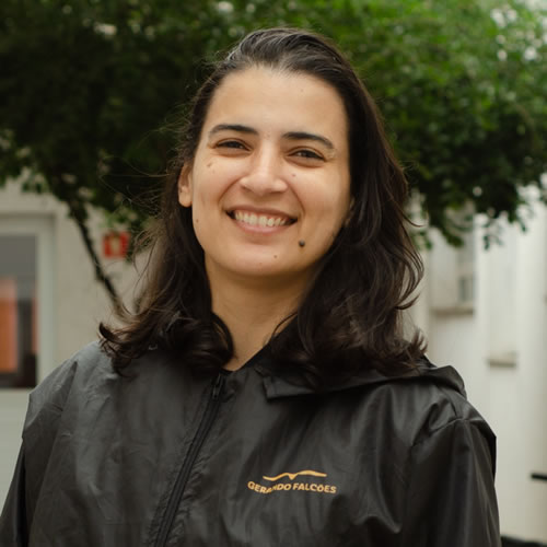 Foto de Priscila Ribeiro - Mestrina orquestra sorrindo para a câmera com uma jaqueta preta da Gerando Falcões