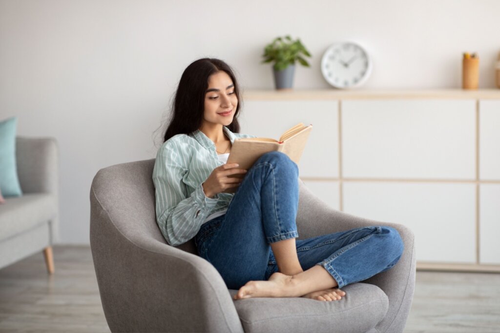 Mulher lendo livro sentada em uma poltrona