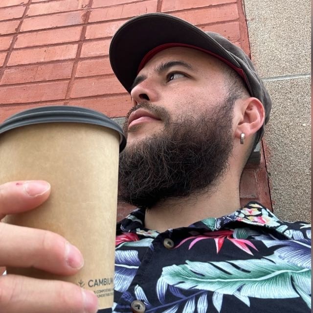 Pressbooks team member Oscar wearing a flowery shirt drinking a coffee