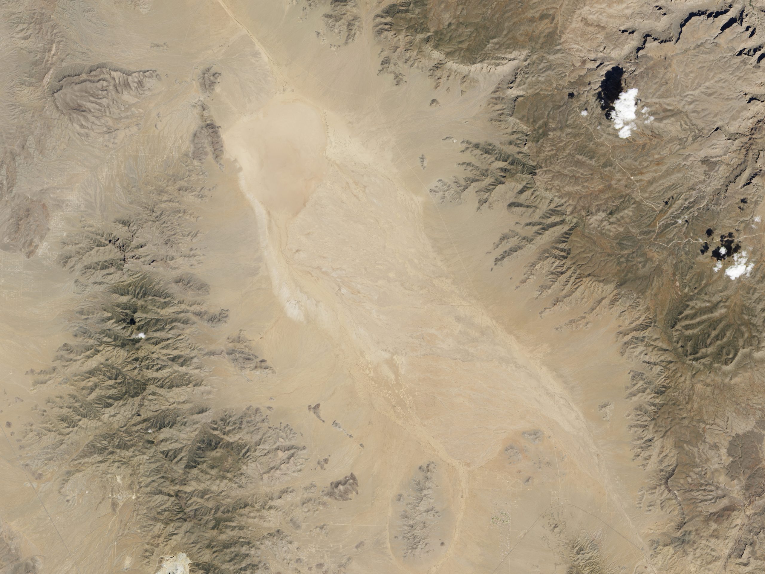 Satellite image of a flat tan desert playa surrounded by mountains on either side.