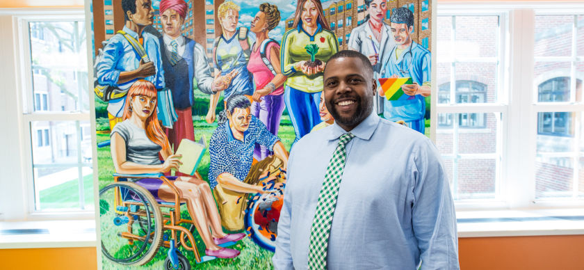 A man stands in front of a mural