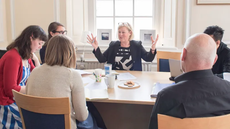 Staff having a discussion round a table with tea and biscuits