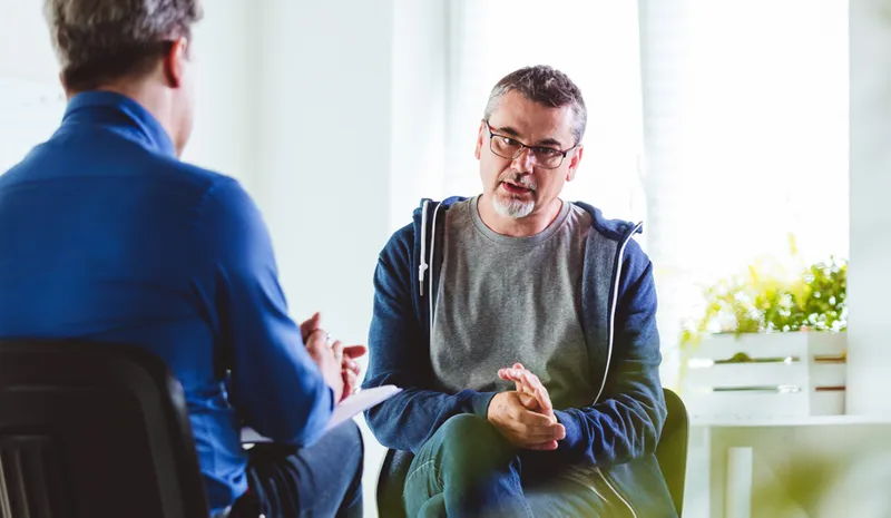 A psychotherapist talking with a depressed man in a psychotherapeutic office