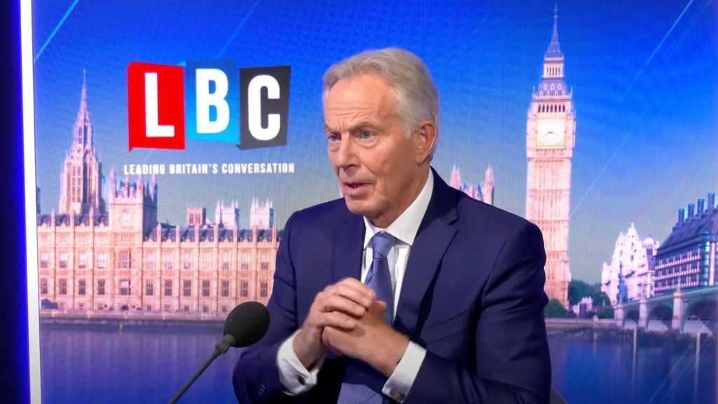 Tony Blair being interviewed at an LBC (Leading Britain's Conversation) studio with Big Ben and the Houses of Parliament in the background.