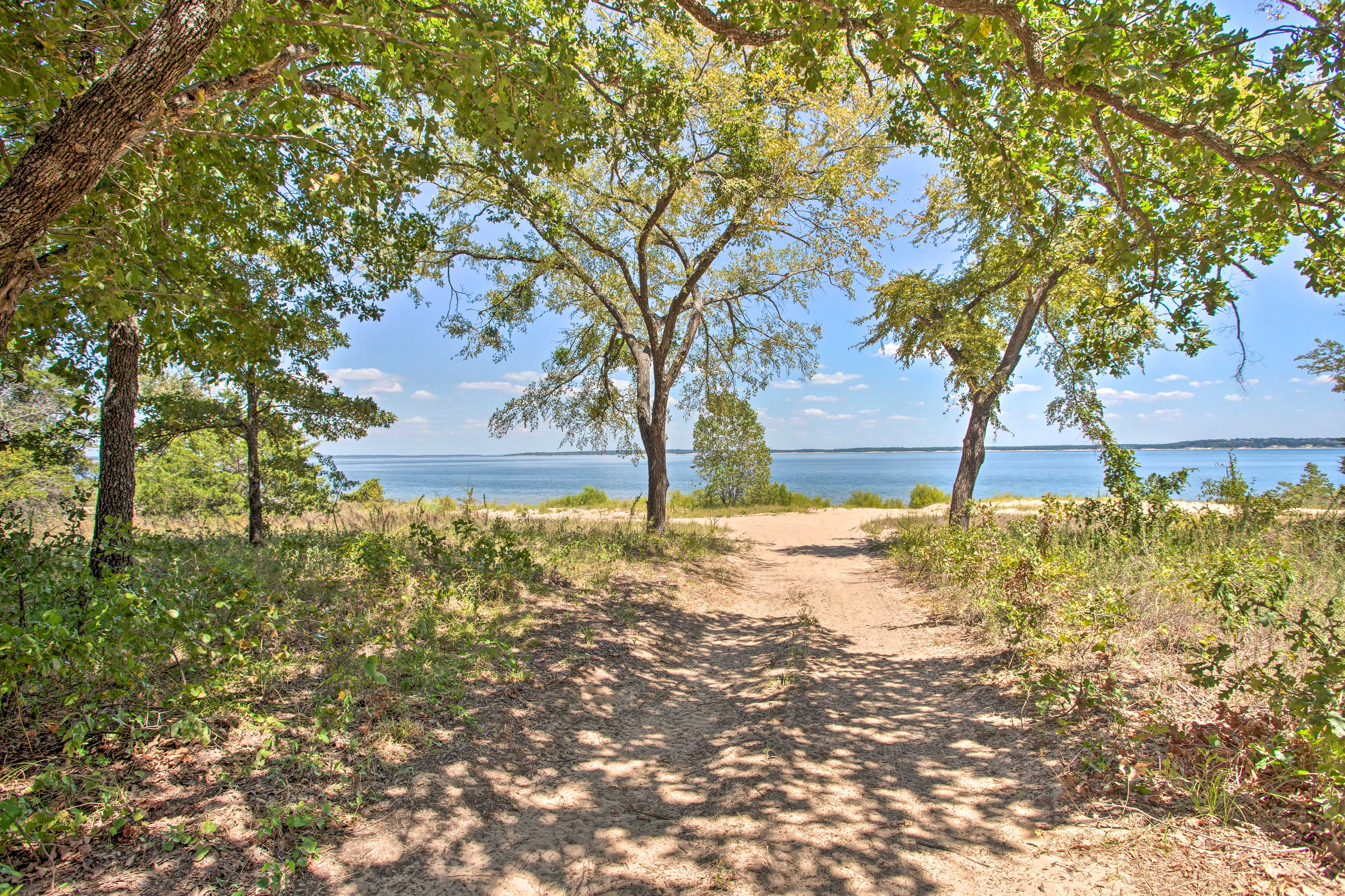 Dirt path leading up to a beach and water with blues skies overhead in Kingston, OK