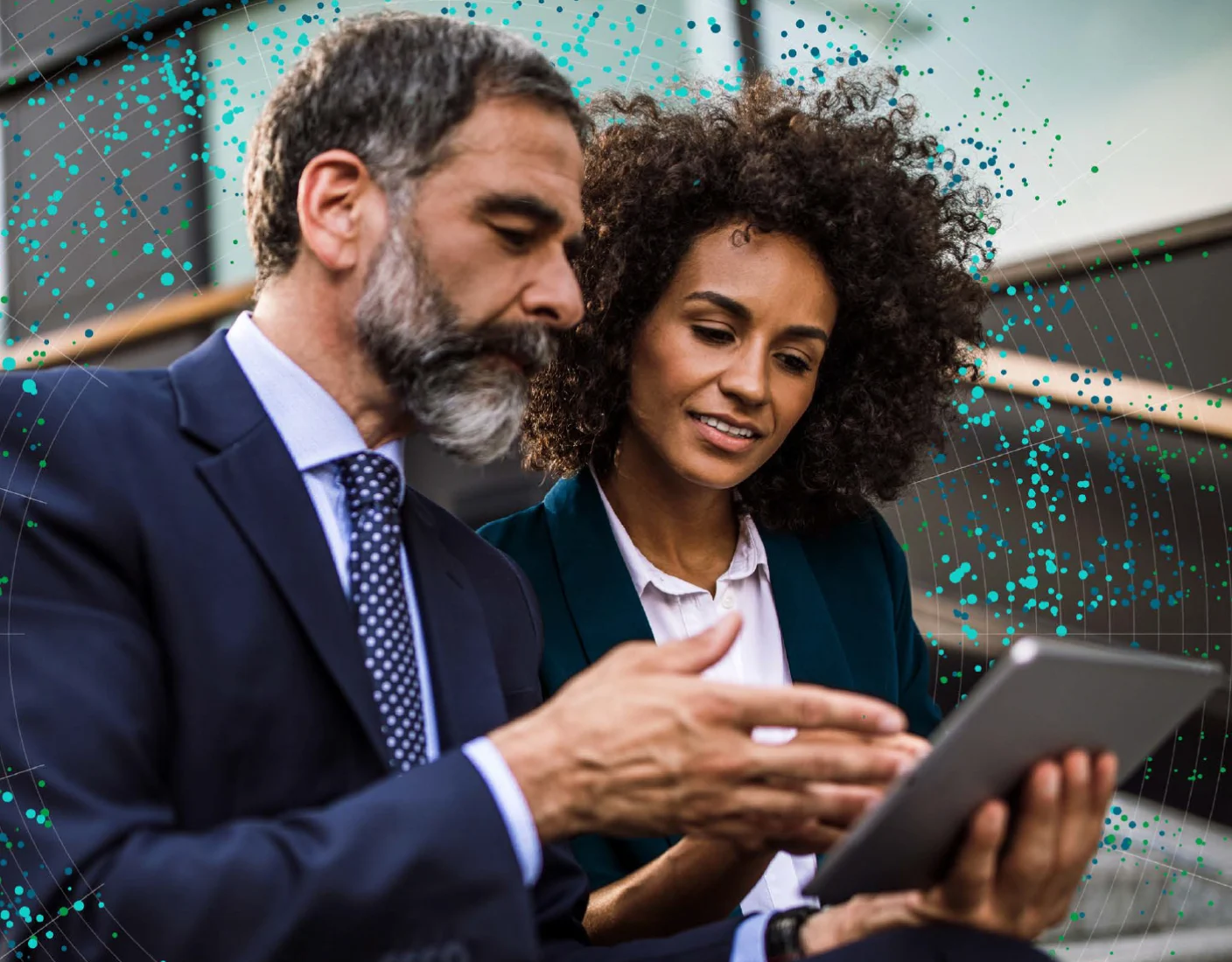 Zwei Fachkräfte, ein bärtiger Mann im Anzug und eine Frau mit lockigem Haar im Business-Outfit, begutachten unter freiem Himmel Informationen auf einem Tablet.