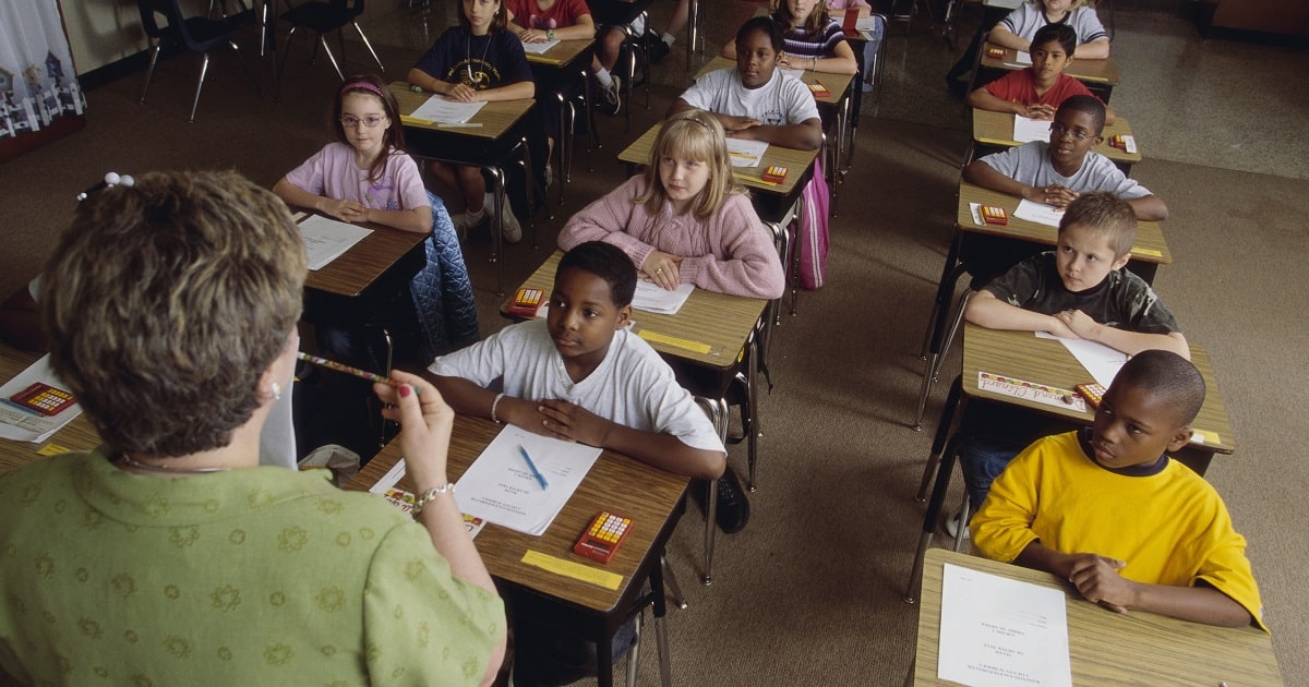 Teaching standing in front of a diverse classroom.