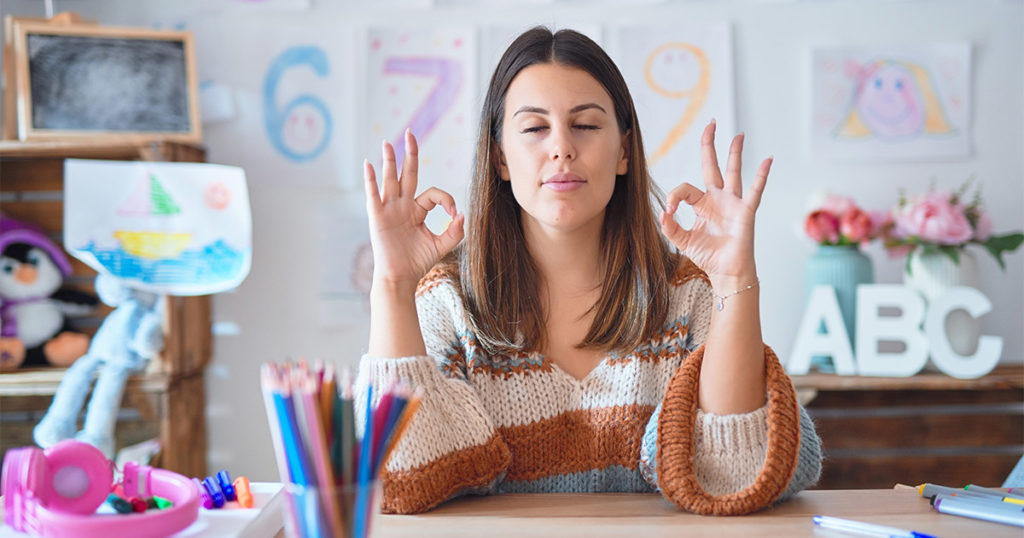 Woman meditating at her desk in school