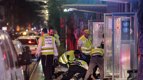 Des volontaires de l'équipe d'intervention d'urgence israélienne ultra-orthodoxe Zaka balayent la scène d'un attentat à la station Ehrlich du tramway de Tel-Aviv à Jaffa, au sud de Tel-Aviv, le 1er oc