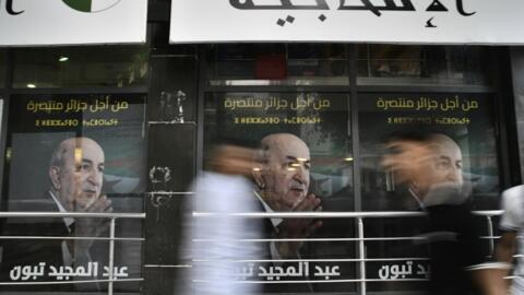 Des gens passent devant des affiches du président algérien Abdelmadjid Tebboune, après l'annonce des résultats de l'élection présidentielle, dimanche 8 septembre 2024, dans la capitale Alger.