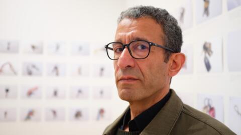 L’artiste palestinien Taysir Batnisi entouré de son installation à la Biennale internationale de Lyon. « Au cas où #2 » est la seule œuvre sur la guerre à Gaza.