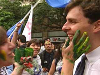 Jovem pinta o rosto do repórter Marcelo Canellas de verde e amarelo durante manifestação de estudantes pelo impeachment do presidente Collor, Jornal Nacional, 21/08/1992.