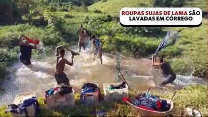 Após chuva, Dinomar dos Anjos, comerciante de Mimoso do Sul, tenta recuperar roupas lavando estoque em córrego.