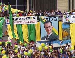 Cena de Anjo Mau em que Olavinho (Gabriel Braga Nunes) toma posse em Brasília e Paula (Alessandra Negrini) comemora ao lado do marido. Enquanto isso, o corrupto Rui (Mauro Mendonça) está preso, mas com muitas regalias.