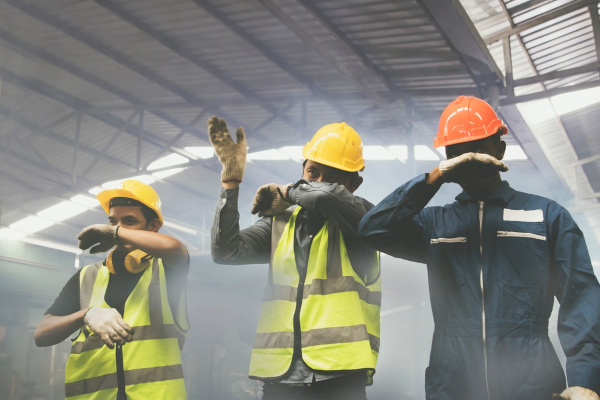 Trabalhadores inalando fumaça, situação que leva à intoxicação por fumaça, um dos efeitos da fumaça no organismo.