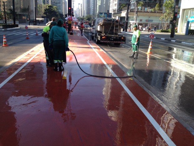 Funcionários da Prefeitura jogam tinta azul que foi jogada na ciclovia (Foto: Vivian Reis/G1)