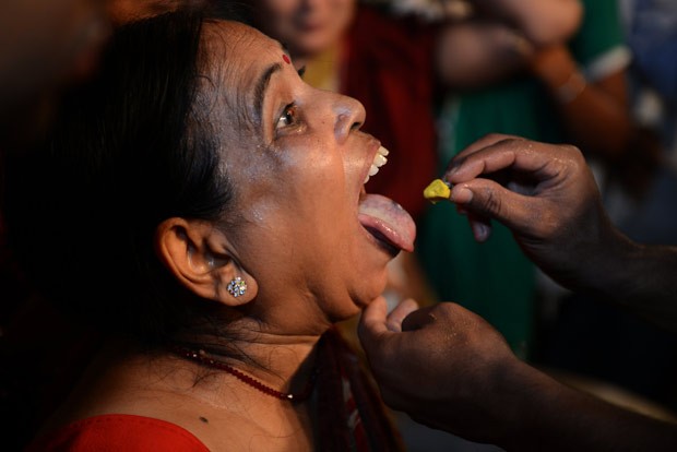 Antes de ser engolido, peixe é mergulhado em erva medicinal (Foto: Noah Seelam/AFP)