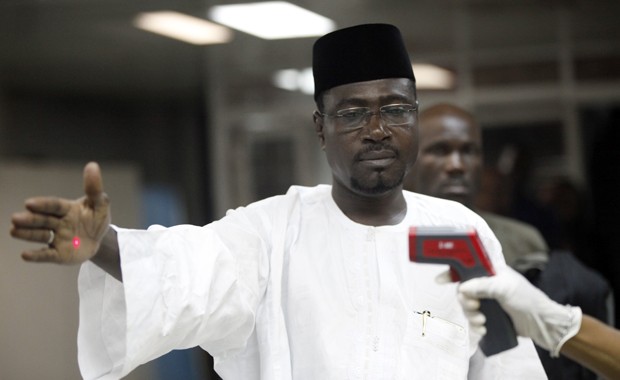 Oficial usa termômetro em passageiro na entrada do aeroporto Murtala Muhammed em Lagos, na Nigéria, em foto de 6 de agosto (Foto: Sunday Alamba/AP)