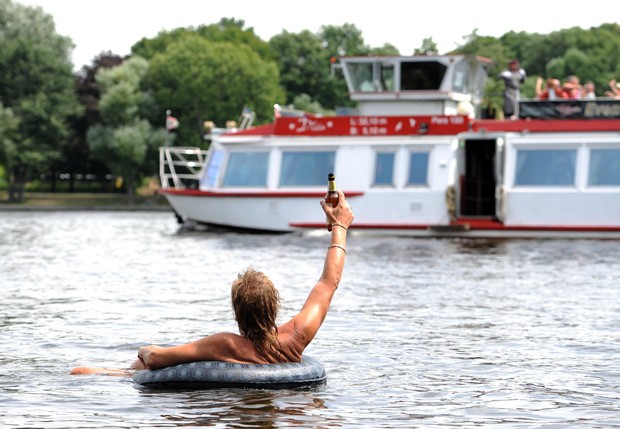 Homem levantou cerveja para 'saudar' embarcação em rio de Berlim, na Alemanha (Foto: Britta Pedersen/AFP)