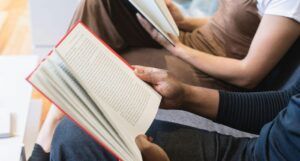 the hands of two people with different skin tones reading books