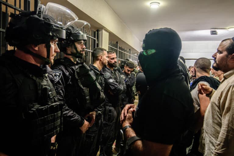 Armed and masked IDF reservists from the '100 force' stand in front of Israeli police officers blocking the Beit Lid base gate following its breach by right-wing activists. Israeli right-wing activists demonstrated with masked IDF reservists from the '100 force' and broke into 'Beit Lid' military police base following the detention of 9 military reservists from the unit today, who were suspected of sexual abuse of a detainee following the October 7 attack in Israel at the 'Sde Teiman' compound.