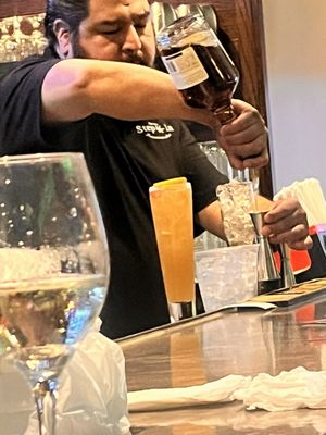 Photo of Step In Restaurant - Bronx, NY, US. The bartender pouring heavy drinks