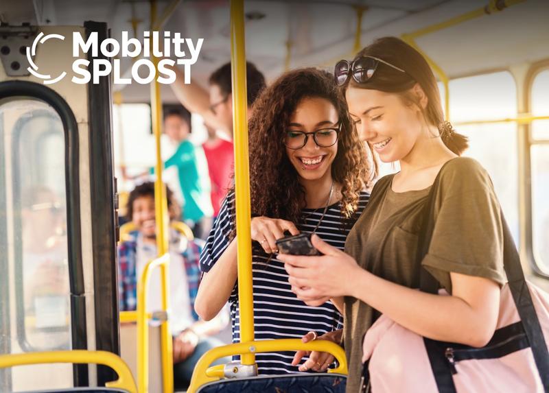 two women looking at a phone on a bus